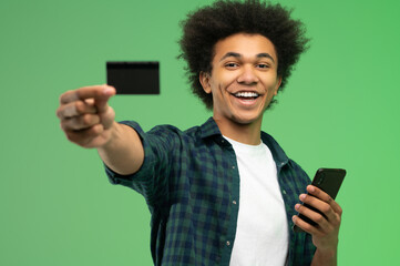 African american young guy with smartphone and credit card in hands