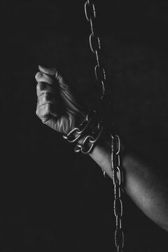 Mano de persona encadenada sobre fondo negro en estudio, sensacion falta de libertad, prision 