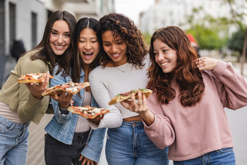 multiracial female friends eating pizza in the city