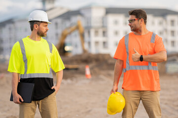 Two builders in a hard hat is busy working on a construction project at a site. A builders workes...