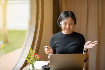 Freelance Asian businesswomen offer ideas or talking  works through online conferences at cafe. Online meeting on labtop, Research and plan, Remote work and communication.