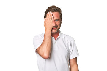 A middle-aged man isolated having fun covering half of face with palm.
