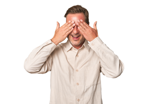 A middle-aged man isolated covers eyes with hands, smiles broadly waiting for a surprise. - Powered by Adobe