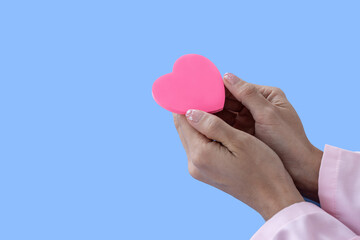 Obraz premium Heart in Doctor's hands on blue background. A Doctor's hand protecting and reassures patient.Healthcare and hospital medical. Organ donation,charity,cardiologist,heart care .Valentine day.copy space.