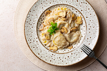 Homemade dumplings filled with mashed potato and mushrooms. Varenyky, vareniki, pierogi, pyrohy. Beige background.