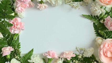 Obraz na płótnie Canvas Spring floral background. Frame made of Pink roses, carnation and fern leaves on white background with copy space for text