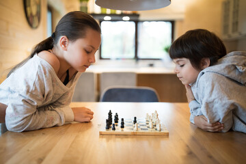 Sister and brother playing chess at home