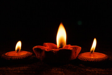 Burning candles in earthenware bowls with orange fire on the floor.