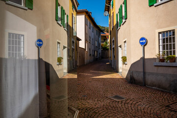 City Road with Old Houses and Window Reflection in a Sunny Day in Arzo, Ticino, Switzerland.
