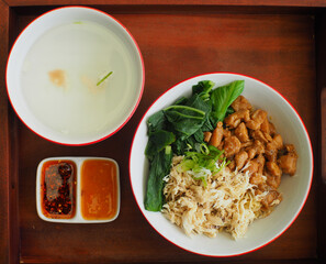 Asian chicken noodles with soup and chili oil on a wooden tray. Top view