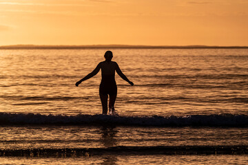 Silhouette of female swimmer going into the Atlantic ocean in Ireland