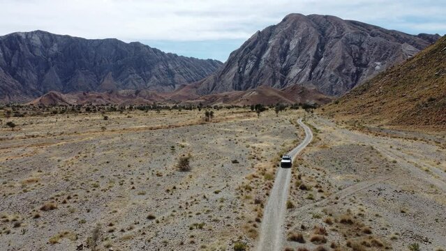 Aerial View Of Car Driving Along Road Through Khuzdar Desert Mountain Landscape