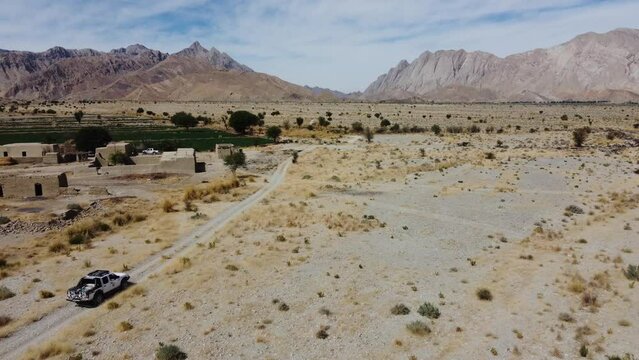 Aerial View Of Car Driving Along Road Through Khuzdar Desert Mountain Landscape. Dolly Forward