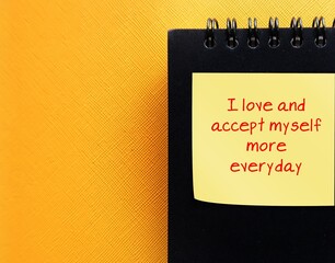 notebook on yellow copy space background with text written  - I accept and love myself more every...