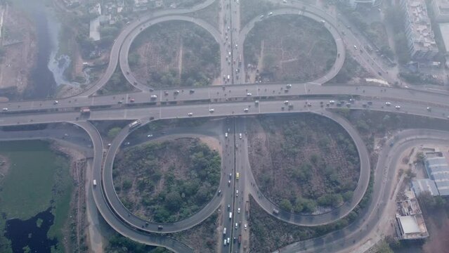 Drone shot of cloverleaf interchange of Maduravoyal flyover bridge drone under smoggy and hazy morning with smooth flowing traffic, Chennai, India