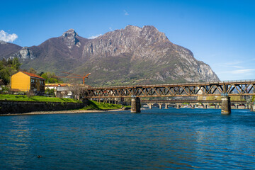 Buildings of the city of Lecco on the banks of the river Adda. Bridges and an island with mountains...