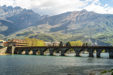 Buildings of the city of Lecco on the banks of the river Adda. Bridges and an island with mountains in the background