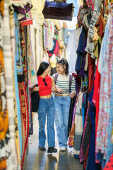Fototapeta na wymiar Two Chinese women tourists shopping clothes in street bazaar