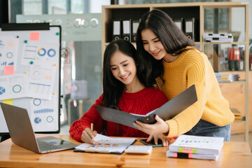 Two Asian businesswoman discuss investment project working and planning strategy with tablet laptop computer in office room.