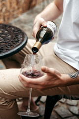 Male hands elegantly pour red wine into a glass