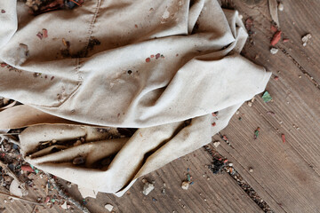 Old faded canvas material and broken pieces of timber piled on the floor