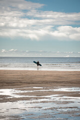 Fototapeta na wymiar silueta de un surfista en la playa entrando en el mar
