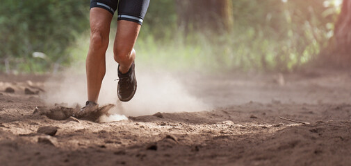 Trail runner running in summer mountain nature landscape on difficult path in mountains, running in a dusty environment in the forest