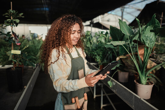 Cool woman working in a greenhouse using a tablet