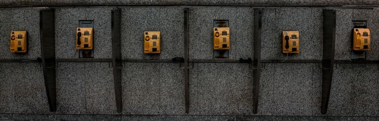 Few old telephones attached to walls in small cabins on the street