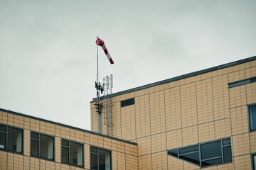 Wind indicator on the top of the building under a cloudy sky.