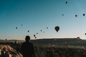 Man watching flying Hot Air Balloon in the blue sky in Cappadocia, Turkey