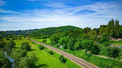 Aerial drone shot of a green meadow with a railroad and a river
