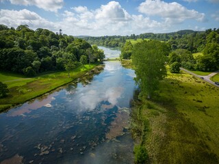 Fototapeta na wymiar Aerial drone shot of the green meadows and a river