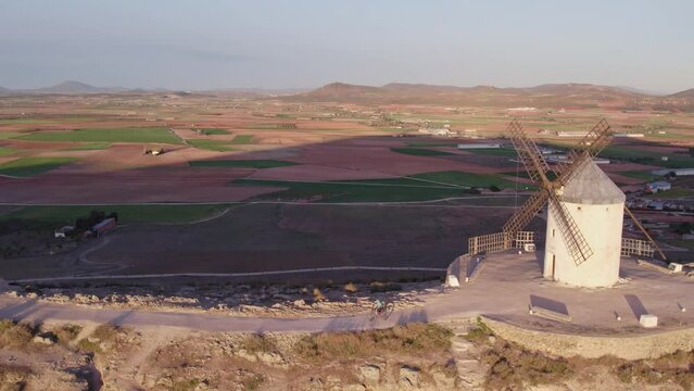 Aerial shot mtb biker athlete riding in front of Molinos de Viento de Consuegra Spain