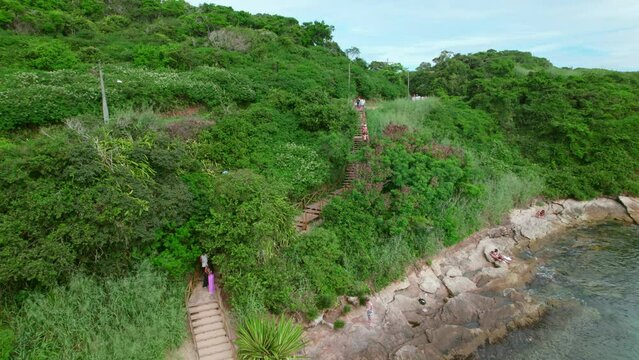 Aerial view towards Praia Azeda staircase winding through lush tropical Brazilian island beach in B&uacute;zios