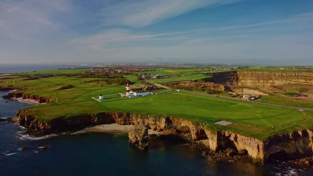 Wide drone orbit of Souter Lighthouse and the lea's, the keepers cottages, cliffs and coastline