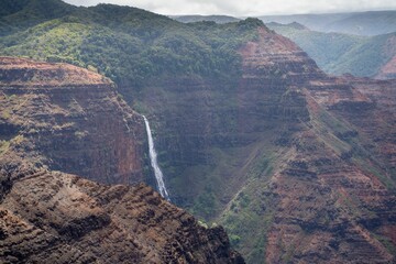 Scenic view of Waipo'o Falls and cliffs in Hawaii under the cloudy sky