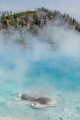 Vertical view of steam over the lake water before the hills landscape