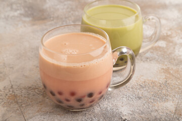 Bubble tea with pistachio and caramel in glass on brown concrete, Side view.