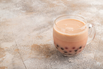 Bubble tea with pistachio and caramel in glass on brown concrete, Side view, copy space.