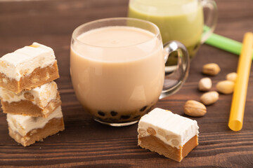 Bubble tea with pistachio and caramel in glass on brown wooden, Side view, selective focus.