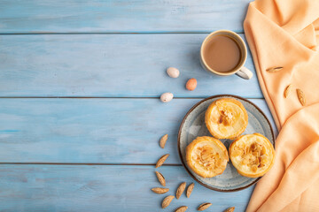 Traditional portuguese cakes pasteis de nata, custard small pies on blue wooden. Top view, copy space.