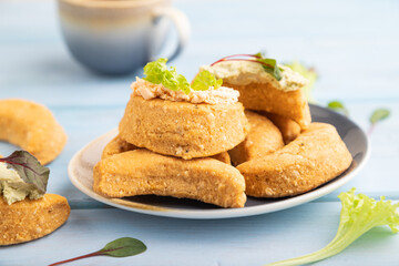Homemade salted crescent-shaped cheese cookies, cup of coffee on blue wooden. side view, selective focus.