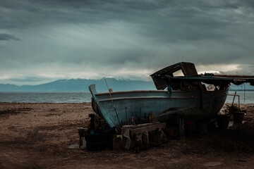 Αbandoned ship on the beach with snowy mountains moody winter