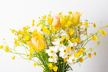 Spring bouquet of yellow buttercups, white daffodils and tulips, bouquet of flowers close up, home decoration with flowers