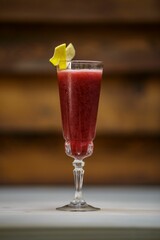 Cocktail in a tall glass with a lemon twist, wooden background