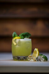 A glass of fresh iced drink with mint and lemon , vertical shot on wooden background