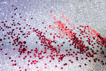 Red glitter confetti abstract silver background, luxury Christmas backdrop with red stars. Brilliant colored sequins. Holiday greeting card.	