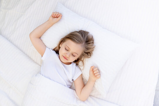 cute baby girl sleeping on a bed on a white cotton pillow under a blanket, healthy baby sleep at night