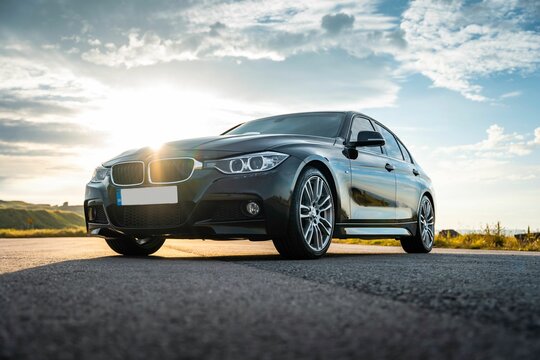 Black BMW 3 under the sunset light, low angle